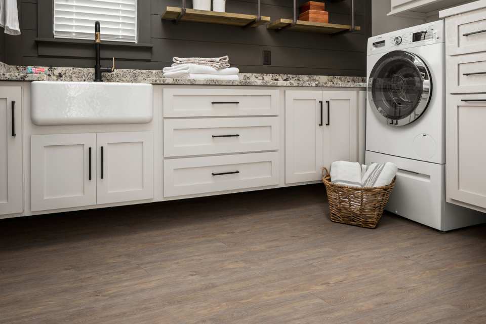 wood look luxury vinyl in modern laundry room with farmhouse sink